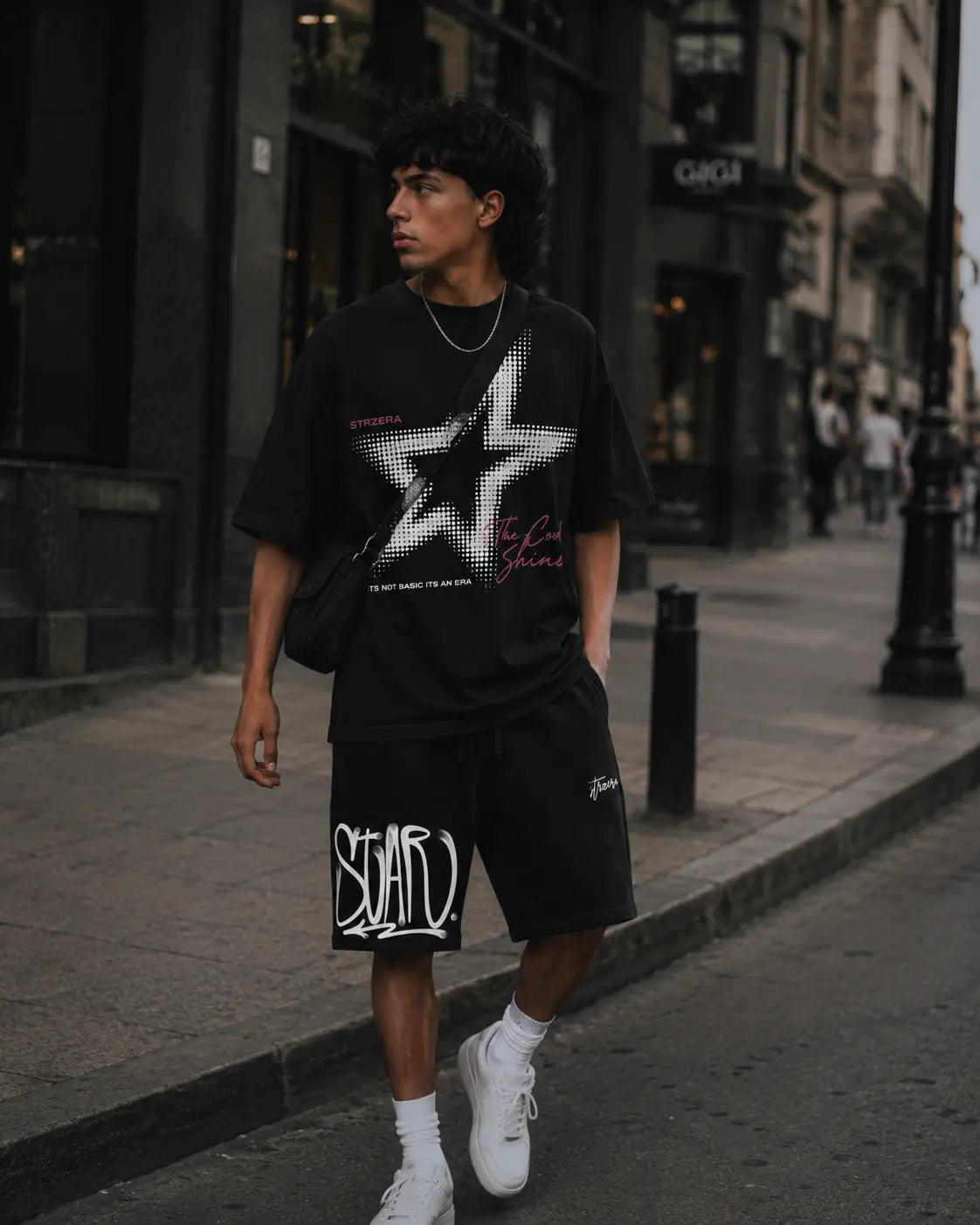 Person wearing a black graphic t-shirt and shorts on a city street.