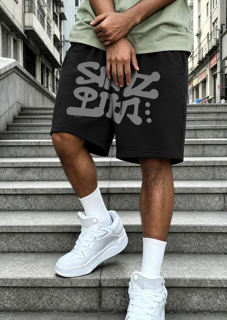 Person wearing black shorts with white text and white sneakers on a staircase.